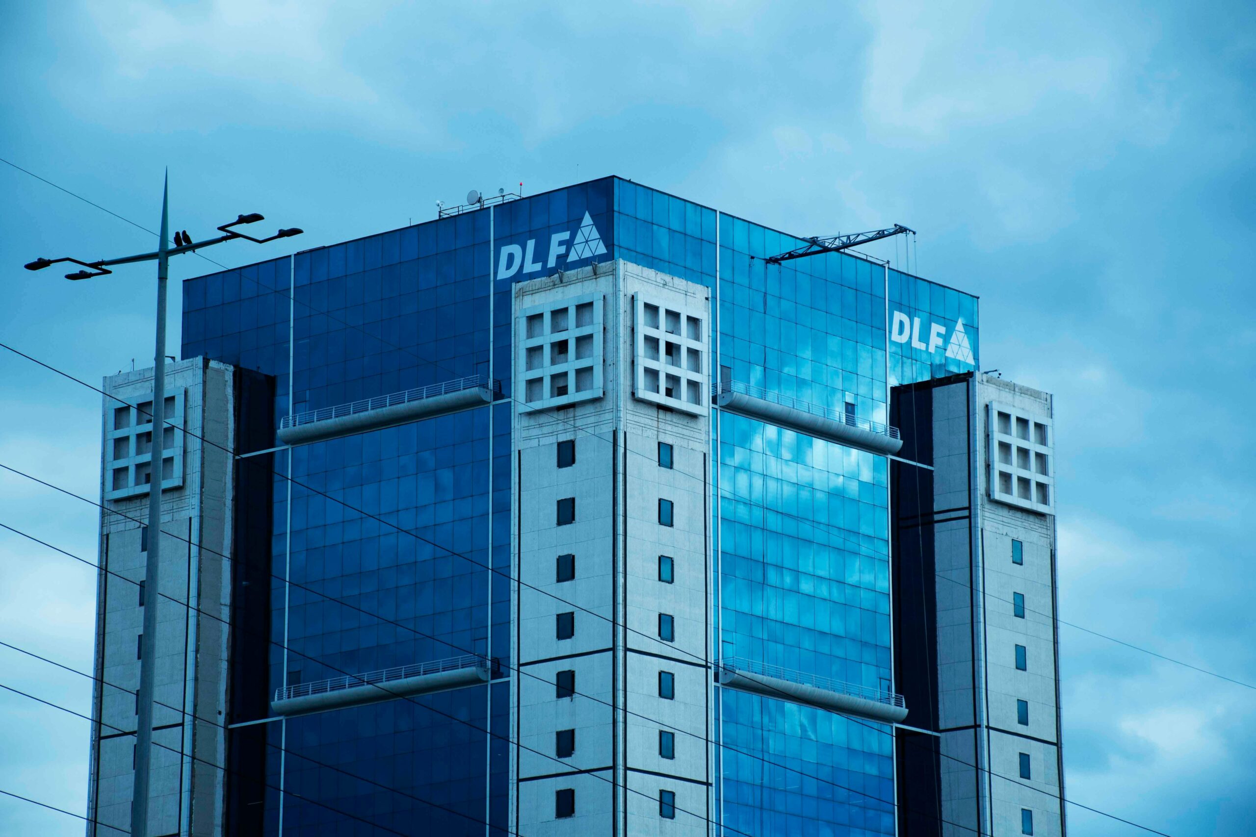 High-rise commercial building DLF Square in Gurugram with glass facade under cloudy sky.